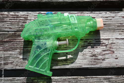 Green water pistol on weathered wood