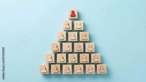 A pyramidal structure of wooden blocks, each imprinted with a silhouette of a person, represents a hierarchy, with a single red figure at the apex