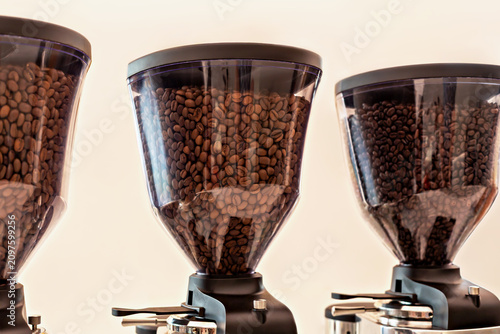Coffee. Three coffee bean grinders with transparent hoppers showcase different types of roasted coffee beans in cafe environment, highlighting rich textures and colors of beans inside containers