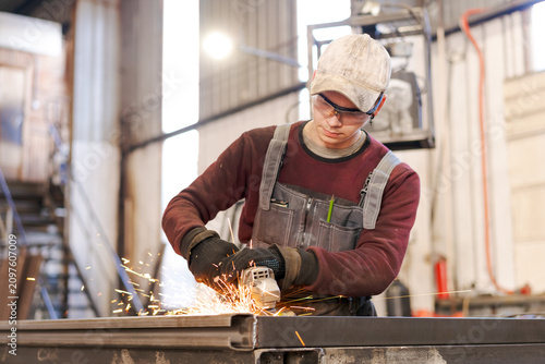 Young Metal Worker Operating Power Tool with Flying Sparks