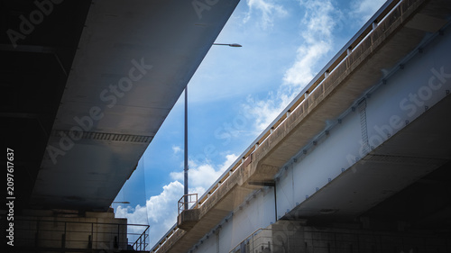 Schilderij op canvas Low angle geometric framing of vibrant blue summer sky between twin highway over