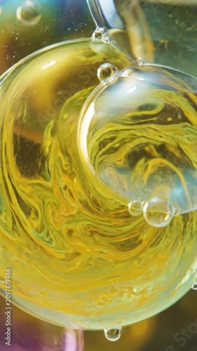Abstract macro shot of swirling yellow and green oil bubbles in water.