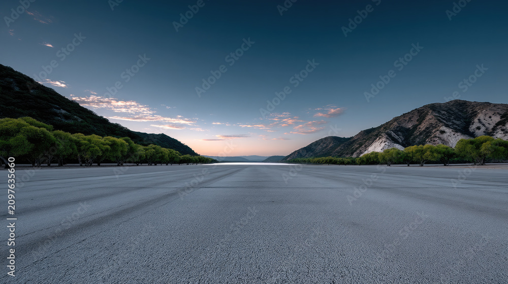 Obraz premium Empty asphalt surface with mountain landscape, green trees, blue sky, and soft sunrise light, peaceful and serene outdoor scene