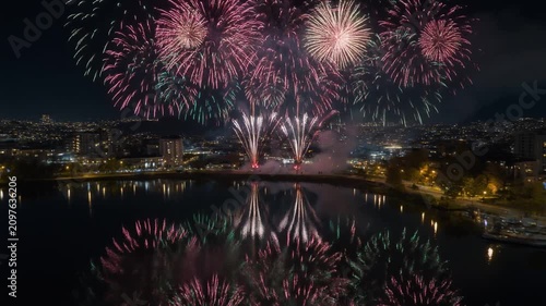 Beautiful fireworks display reflecting on the water surface over a city at night during celebration