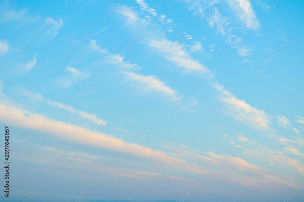 Fototapeta premium Beautiful sunset sky landscape, sweeping panoramic view of pink and orange clouds in blue sky lit by evening sunlight