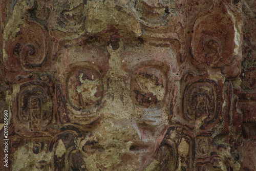 Fotografia Front view macro shot of ancient Mayan stone carved face with red pigment