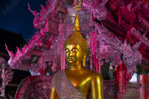 Vászonkép Golden Buddha statue illuminated at night in front of ornate silver temple archi