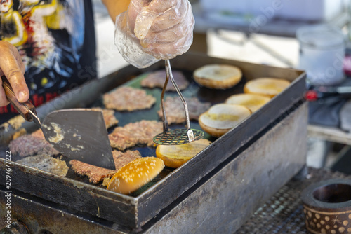 Fotografía Grilling burger patties and toasting sesame buns on flat top griddle at outdoor