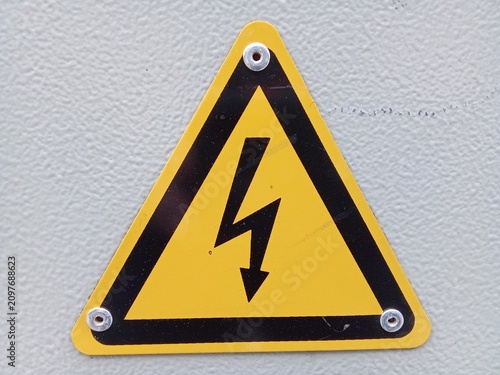 Close-up of yellow triangular sign warning of high voltage electrical hazard