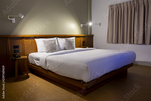 Cuadro en lienzo Modern minimalist hotel room with neatly made double bed, white linens, two deco