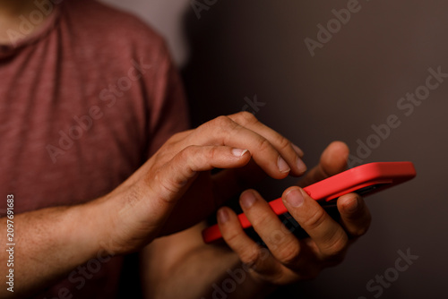 A person's hands interact with a bright red smartphone screen.