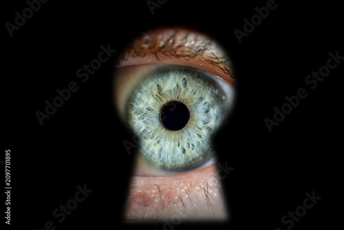 Fotografie Eye looking through keyhole observing and spying secrecy