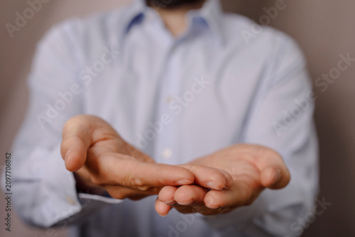 Tableau sur toile A person in a blue shirt gestures with open hands, implying giving or receiving, offering help