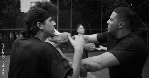 Foto Two men of Latin and African descent arguing face to face on outdoor basketball
