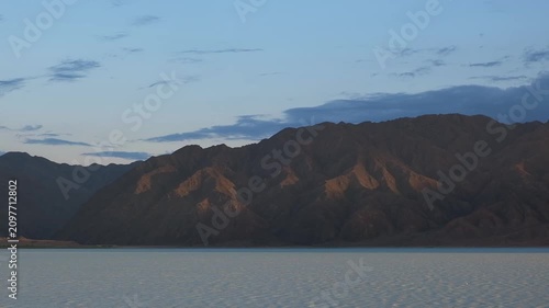 Wide shot of desert mountains and a vast lake with water ripples caused by wind. Universal landscape background suitable for cinematic commercial layouts, travel, and media production.