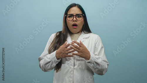 Konstfotografi Young female doctor with hand on chest and other hand raised in stop gesture in studio; anxiety concern