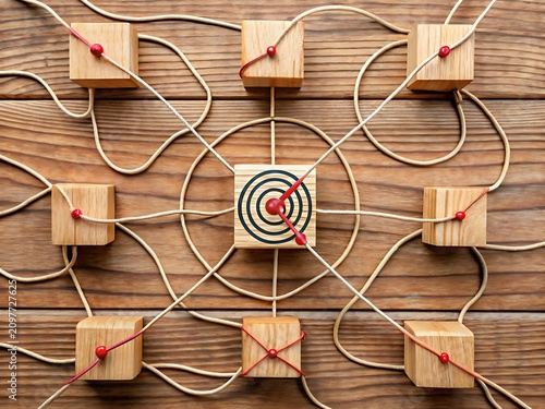 Wooden blocks connected by strings to a central target block on a rustic wooden surface