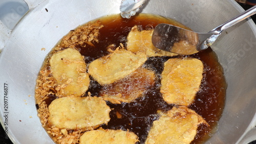 Bild auf Leinwand Fresh fritters sizzle in hot oil until crispy and golden, reflecting traditional Indonesian snack preparation with authentic homemade cooking techniques