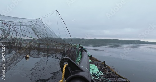 Large fish farm in the water with nets under cloudy sky as background