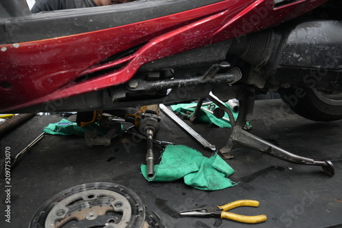 Red scooter undergoing maintenance on a workshop lift table.
