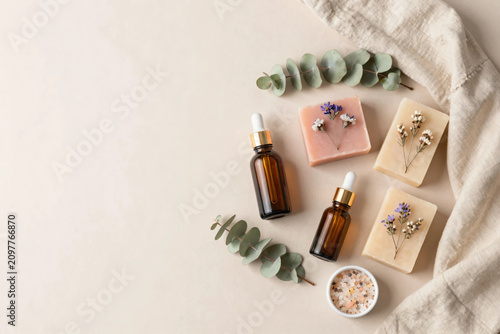 Premium Flat Lay of Natural Herbal Skincare Products with Botanical Soaps, Amber Serum Bottles, Bath Salts, and Fresh Greenery on Soft Pastel Background for Clean Beauty and Wellness Branding