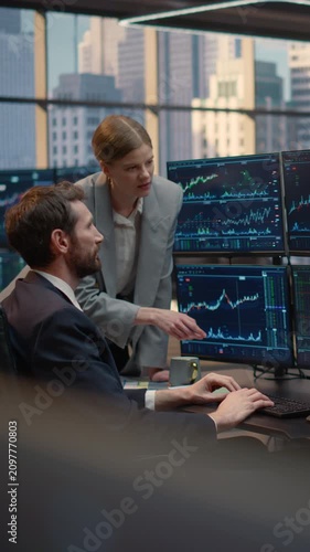 Vertical Screen. Two Brokers, a Man and Woman, Collaborate at a Desk, Pointing at Stock Market Data and Financial Charts, Discussing Trading Strategy and Investment Portfolio Growth as a Team.