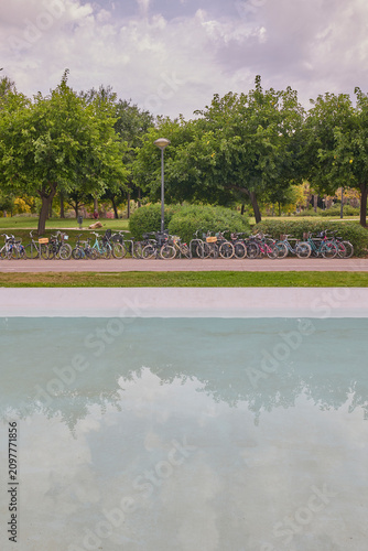 Row of parked bicycles beside green park in Valencia Spain