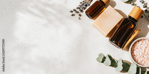 Premium Flat Lay of Natural Herbal Skincare Products with Botanical Soaps, Amber Serum Bottles, Bath Salts, and Fresh Greenery on Soft Pastel Background for Clean Beauty and Wellness Branding