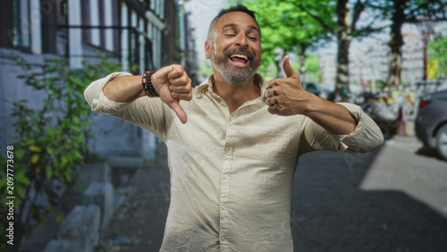 Canvas Print Man showing thumbs up and thumbs down gestures on a city street with visible hands and beard; ambivalence decision