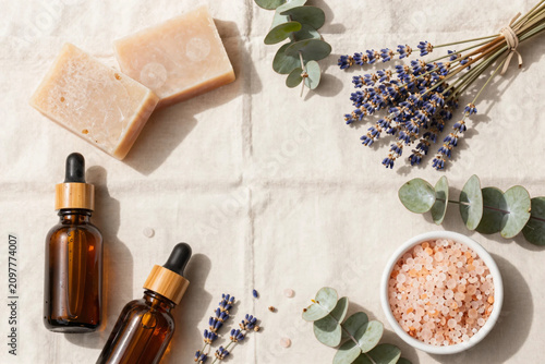 Premium Flat Lay of Natural Herbal Skincare Products with Botanical Soaps, Amber Serum Bottles, Bath Salts, and Fresh Greenery on Soft Pastel Background for Clean Beauty and Wellness Branding