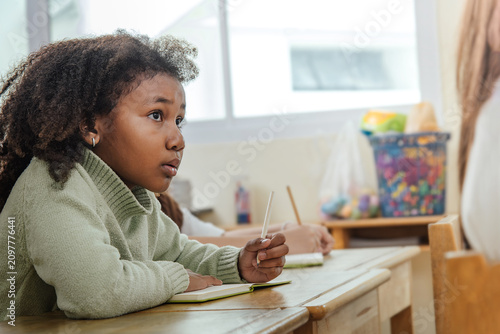 Foto Young Generation Alpha schoolgirl practises handwriting with concentration in br