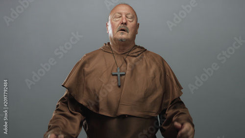 Foto Man monk covering face with hands, wooden cross pendant visible over brown robe in studio; penance despair faith