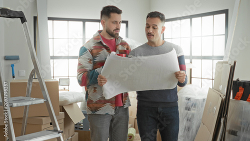 Foto Man holding blueprint with both hands and reading plan in an apartment full of boxes and ladder; home planning anticipation