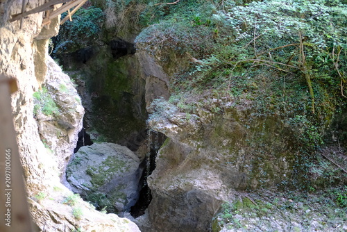 Narrow rocky canyon with mossy cliffs and dark cave entrance in nature