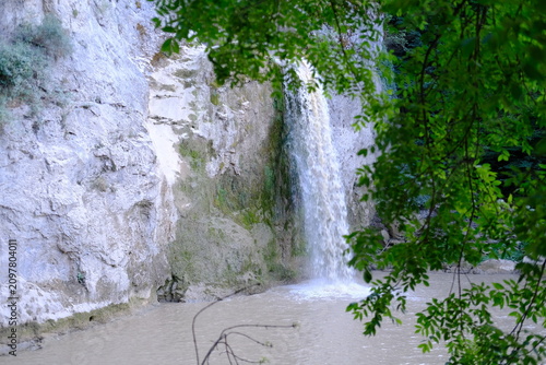 Beautiful waterfall cascading down white rock cliff surrounded by green foliage