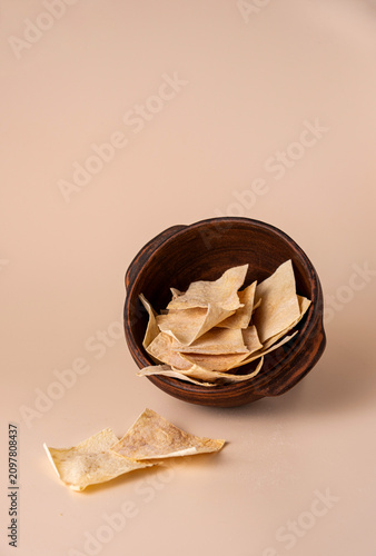 Armenian lavash chips in a clay bowl on a beige background; space for text.