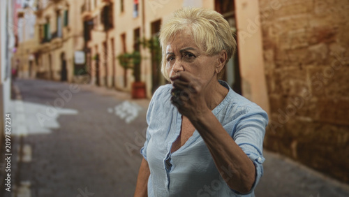 Foto Woman points finger like gun with clenched hand and tense forearm visible on a narrow cobblestone street; defiance