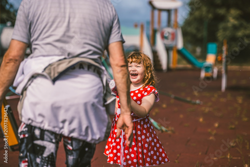 Happy child playing with man on outdoor playground. Little girl laughing while interacting with grandfather. Joyful moment of family connection, childhood leisure and recreation activity.