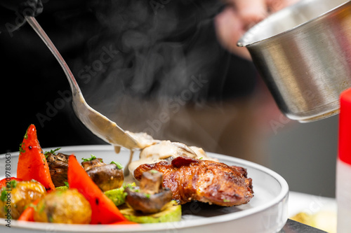 Fotografía Chef pouring creamy mushroom sauce over grilled chicken steak with roasted vegetables