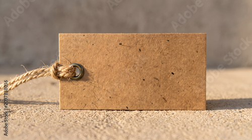 Blank kraft paper hangtag mockup on textured concrete surface