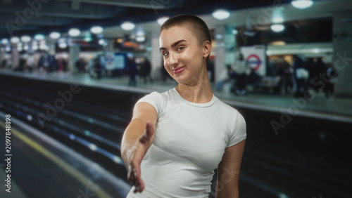 Foto Woman extends right hand for handshake on a subway platform at a station, short hair and white t shirt visible; welcome invitation