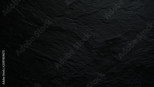 Black slate stone texture background with rough natural surface and cracks
