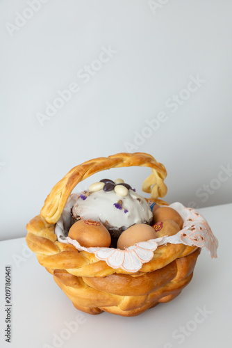 Easter bread basket with decorated cake and eggs on white background