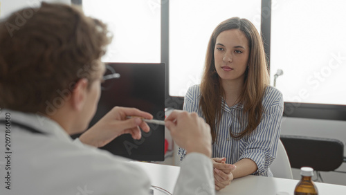 Schilderij op canvas Woman covers face with hands while doctor with stethoscope gestures holding a penlike tool at a consultation in a building; anxiety concern