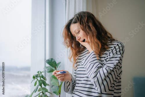 Foto Young woman receiving an unexpected positive pregnancy test result, experiencing