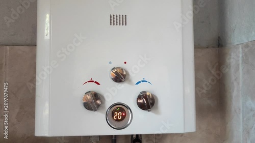White gas water heater being switched on with temperature control display showing 48 degrees in residential home interior.