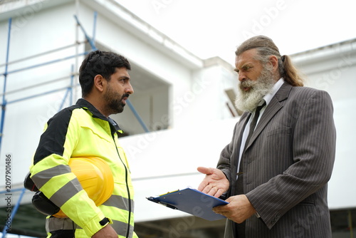Construction Engineer Discussing Building Project Issues with Senior Client at Construction Site
