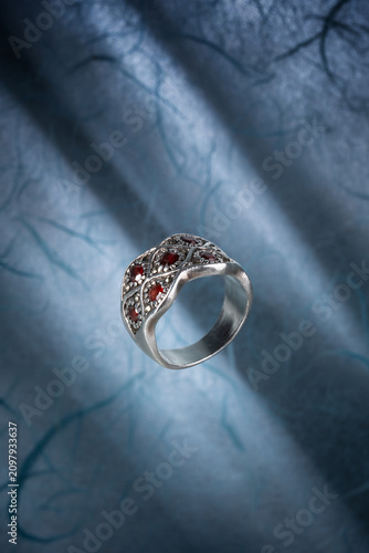 Boho style band ring is crafted from 925 sterling silver and features natural red garnet stones, photographed on light blue parchment