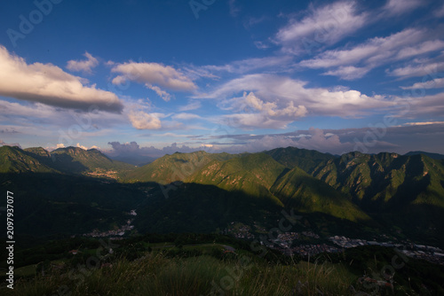 Tableau sur toile Alpine valley landscape with village and dramatic cloud formations, Lombardy, Italy, Val Trompia