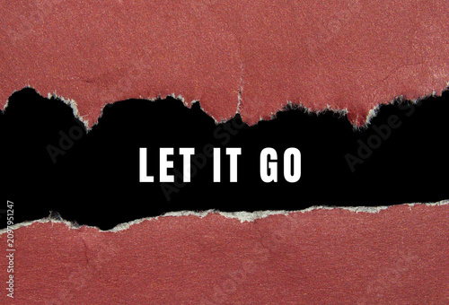 Fotografie Ripped red paper creating a black space with a let it go text, symbolizing relea